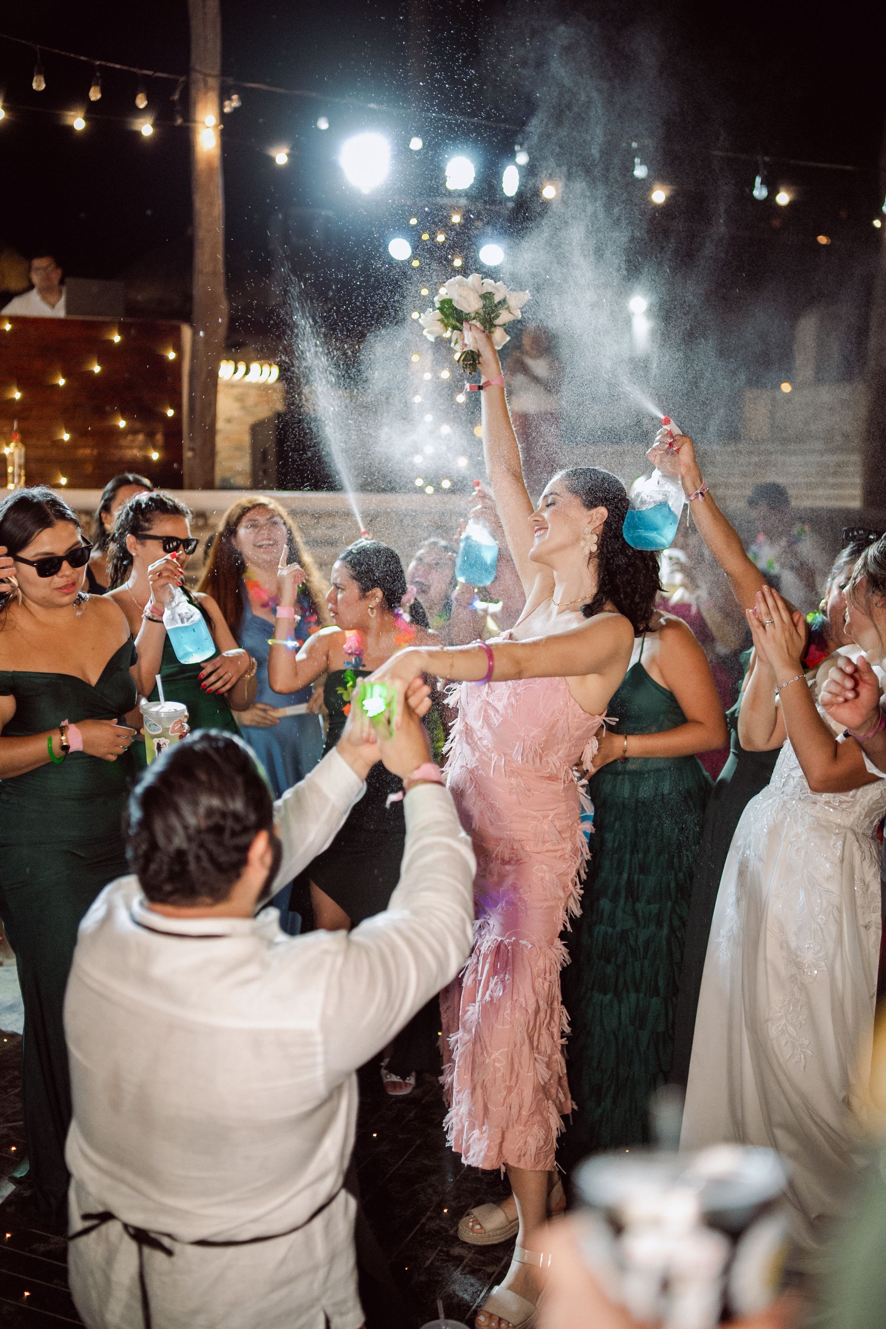 Wedding guests celebrating together beneath string lights